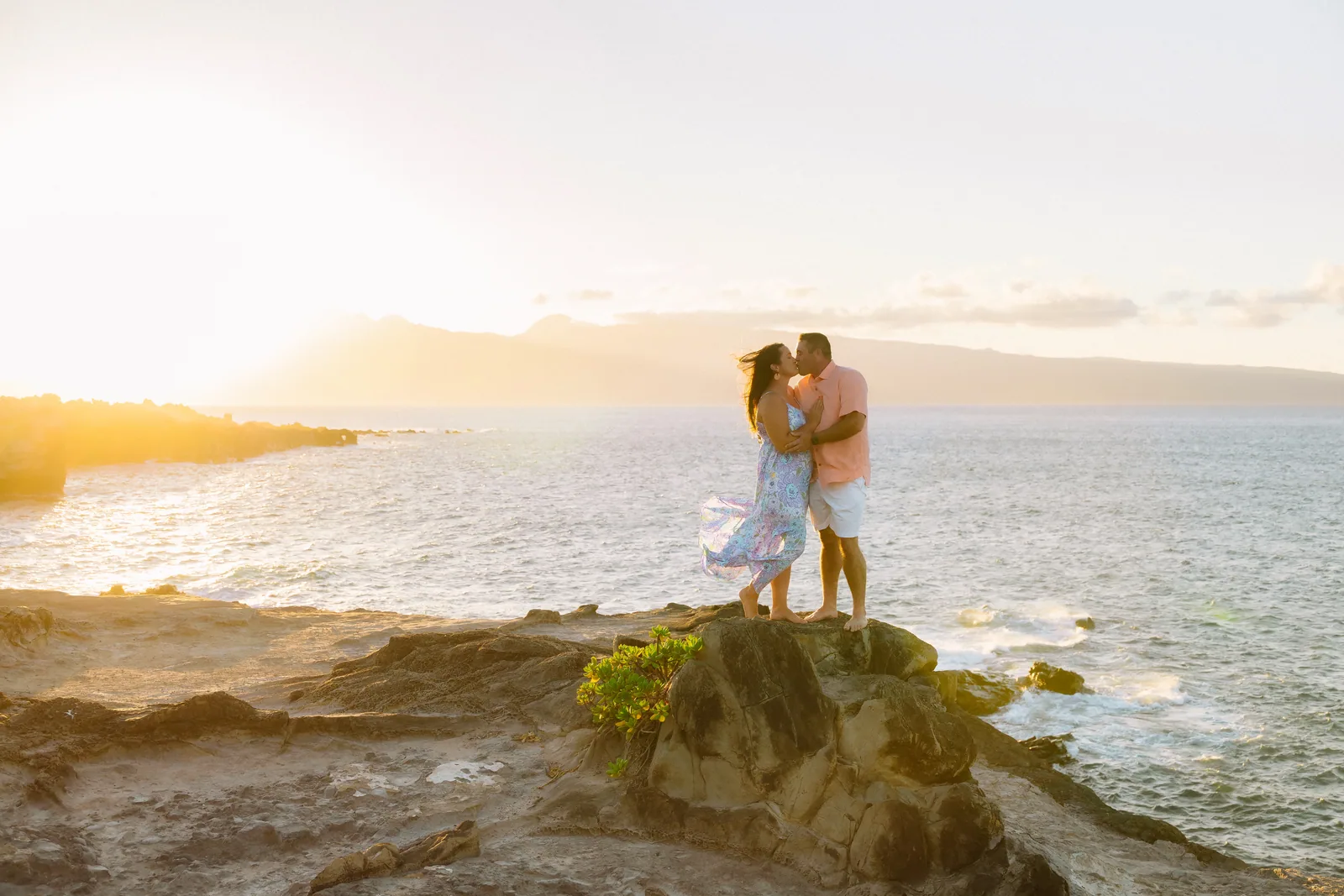 A couple embracing on a rocky headland with open ocean behind them