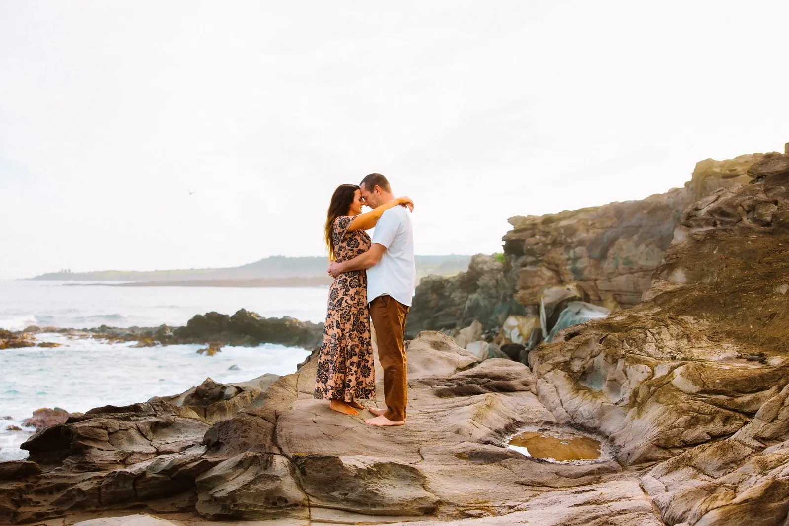 Couple embracing on a cliffside above the water on Maui