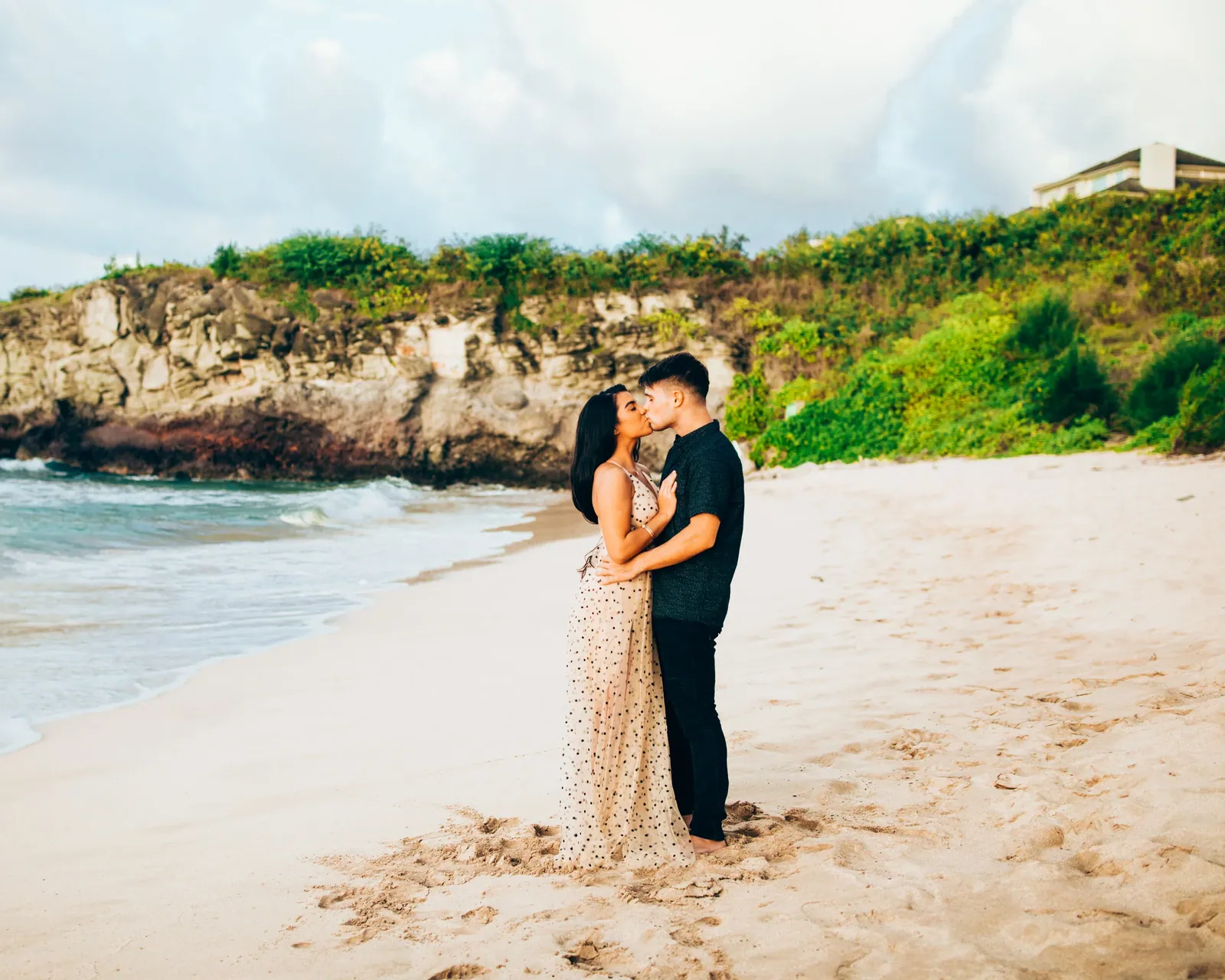 Couple standing together in a quiet Maui cove framed by sea cliffs
