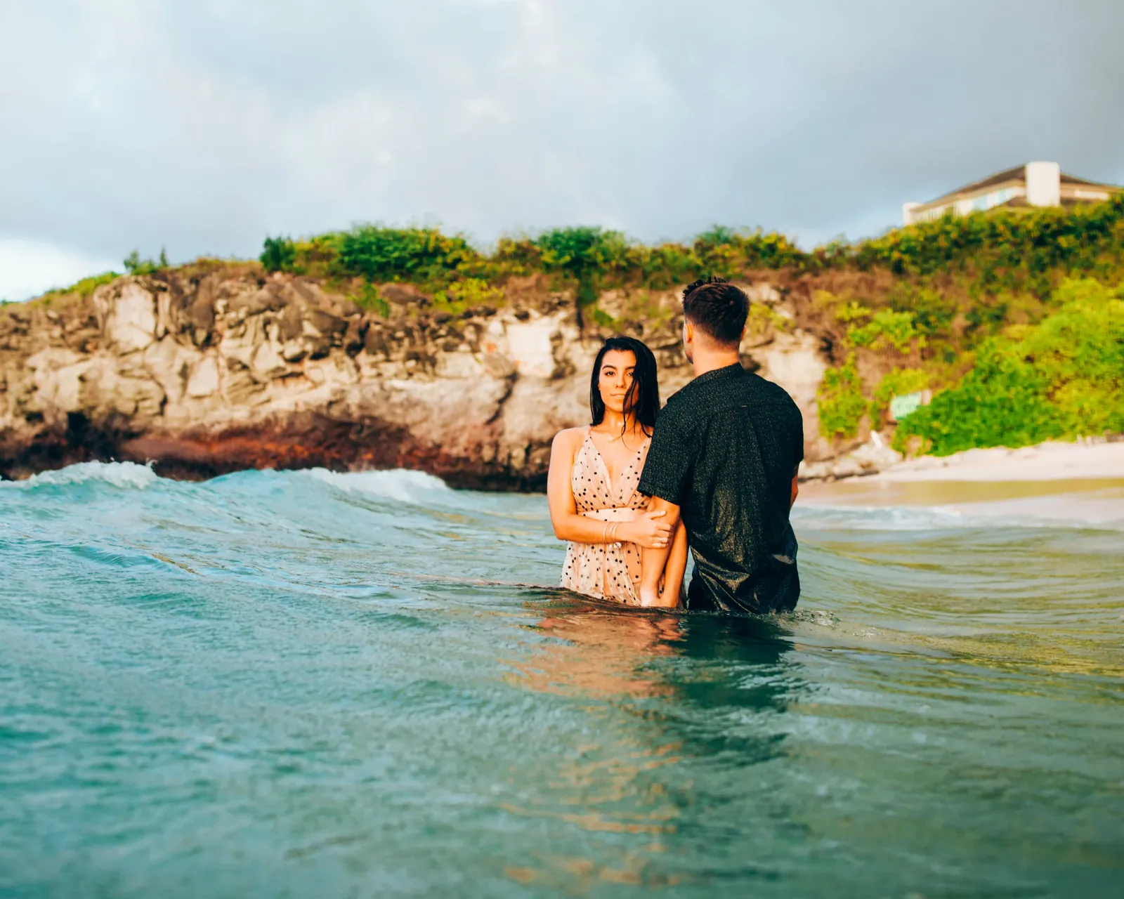 Couple standing waist-deep in clear water during a Maui ocean session