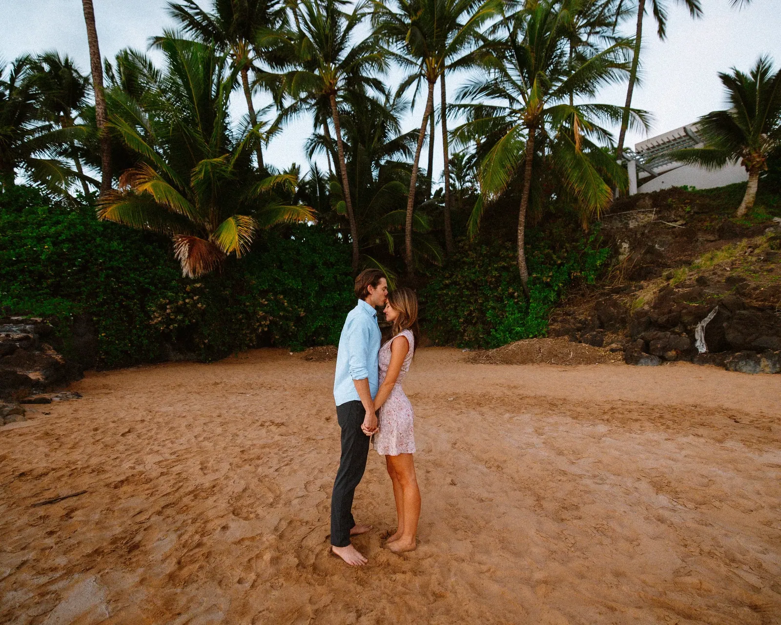 Couple standing close together in a palm grove on the Kihei coastline