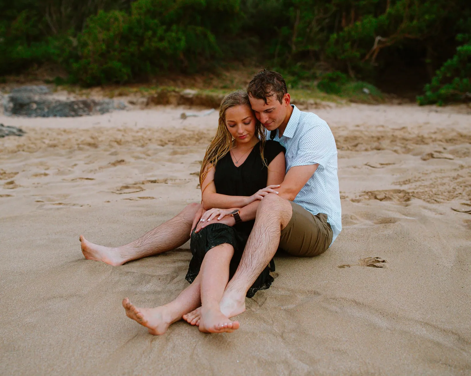 Couple sitting on the sand in a quiet cove on Maui