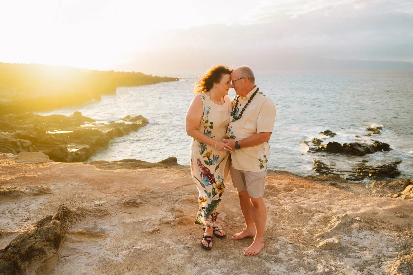 A couple kissing in a small cove as the sun sets behind the point