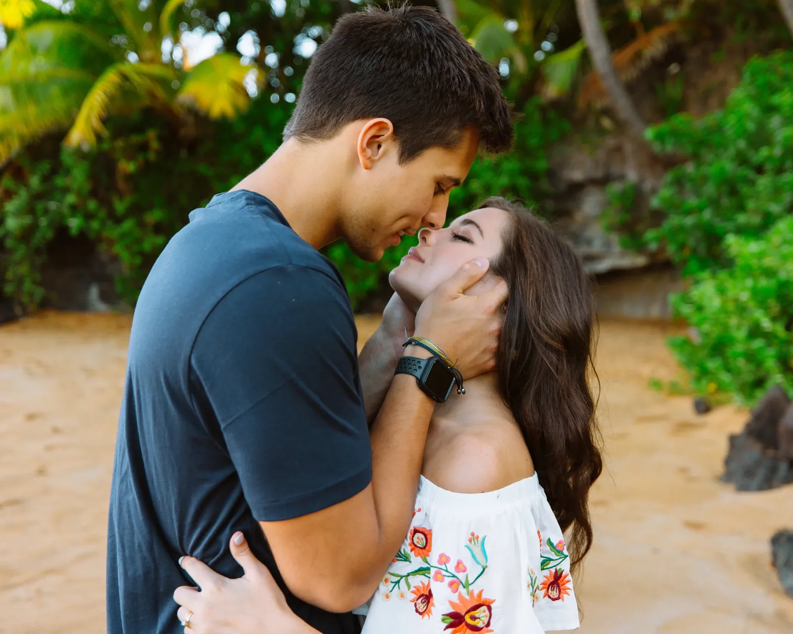 Couple laughing mid-kiss during a golden-hour session on a Wailea beach, Maui