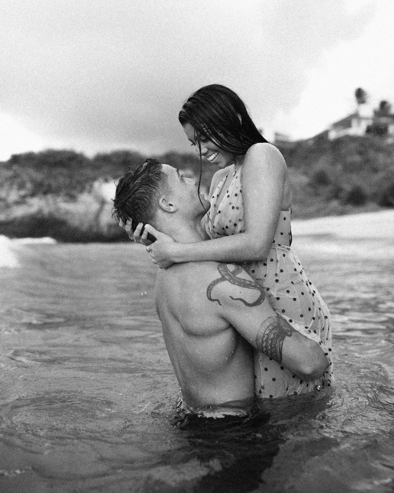 Black and white image of a couple embracing in the surf on Maui