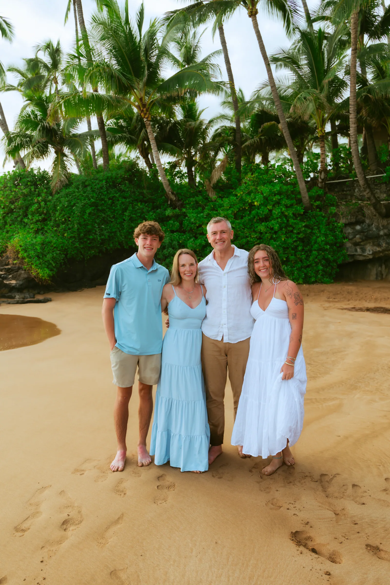 A family of five photographed under palms at the top of the beach