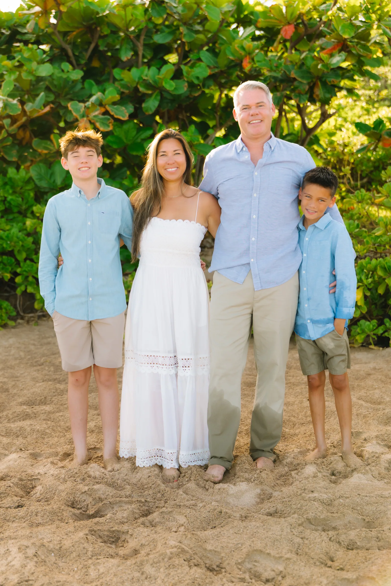 A family of four photographed against thick green coastal growth