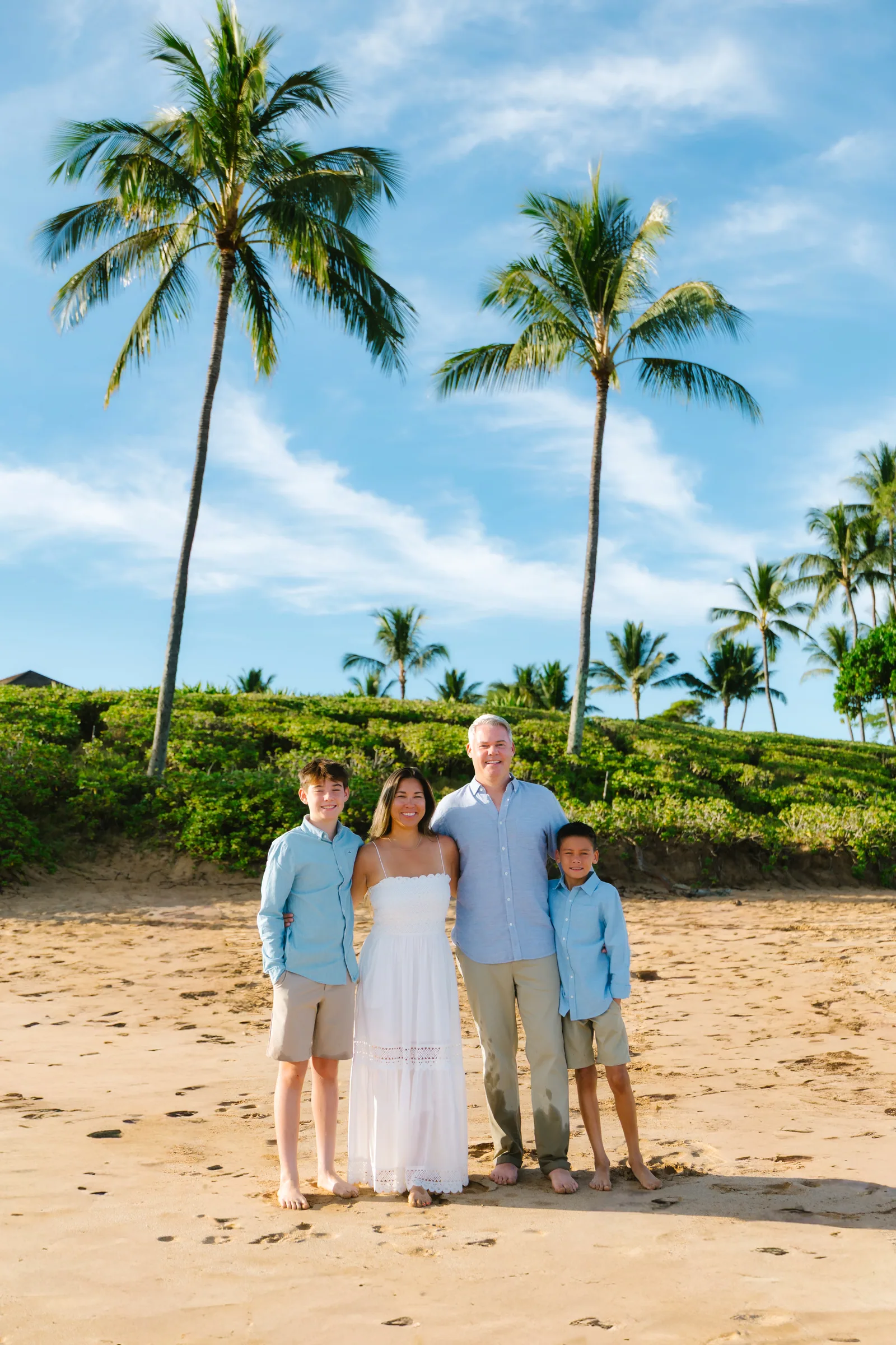 A family of four photographed together under tall coconut palms