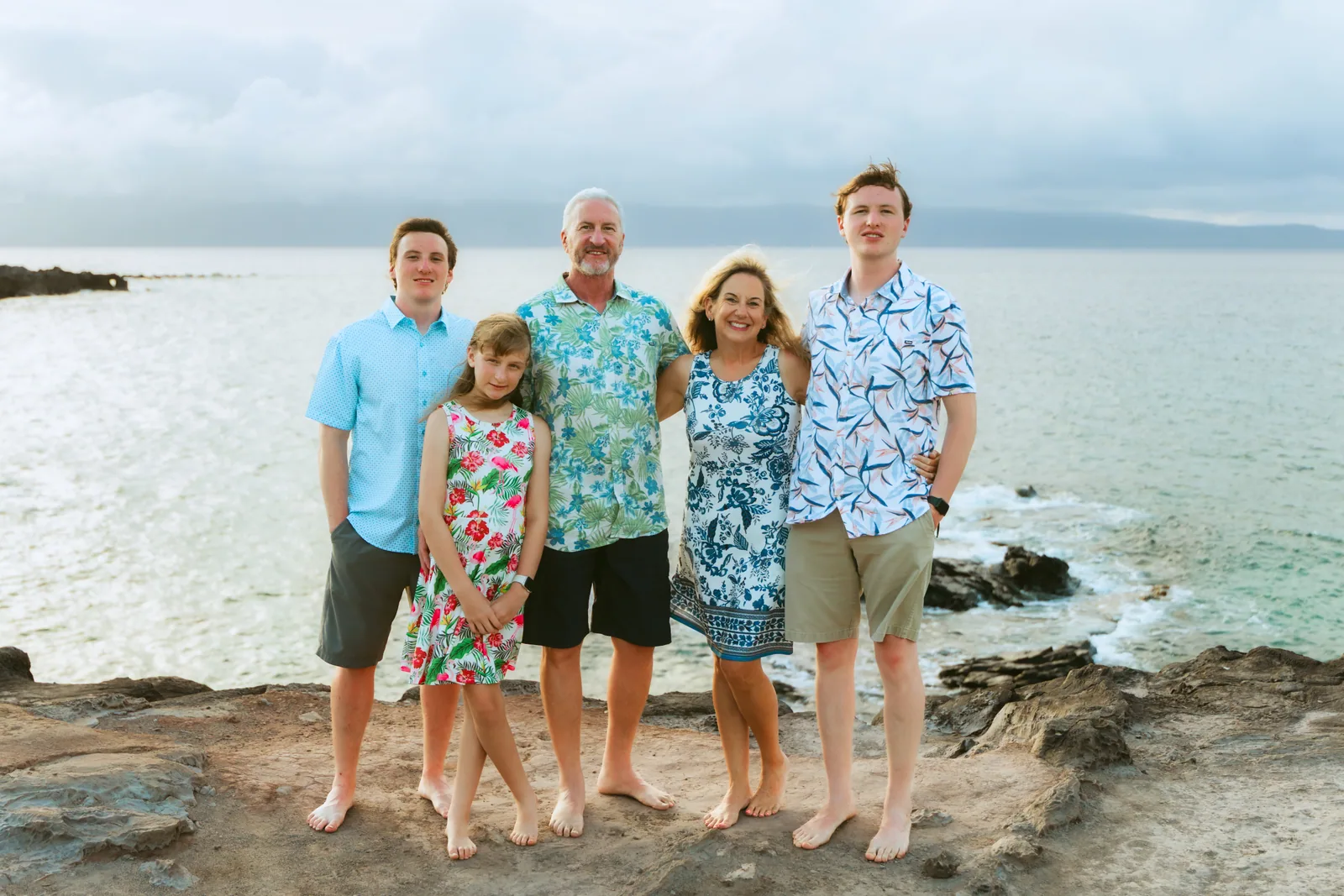 A family standing along a lava shelf with the ocean behind them