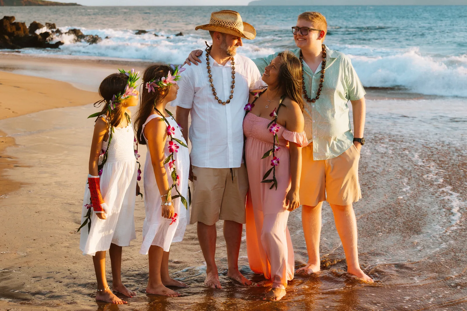 A family in leis photographed together along the shoreline