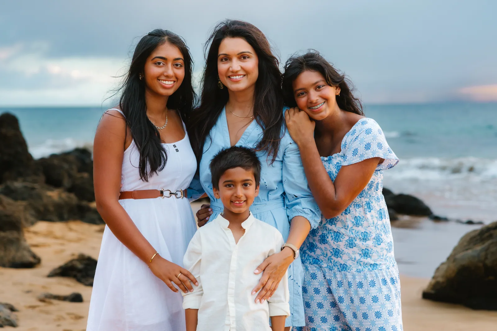 A mother and her children photographed together beside coastal rocks