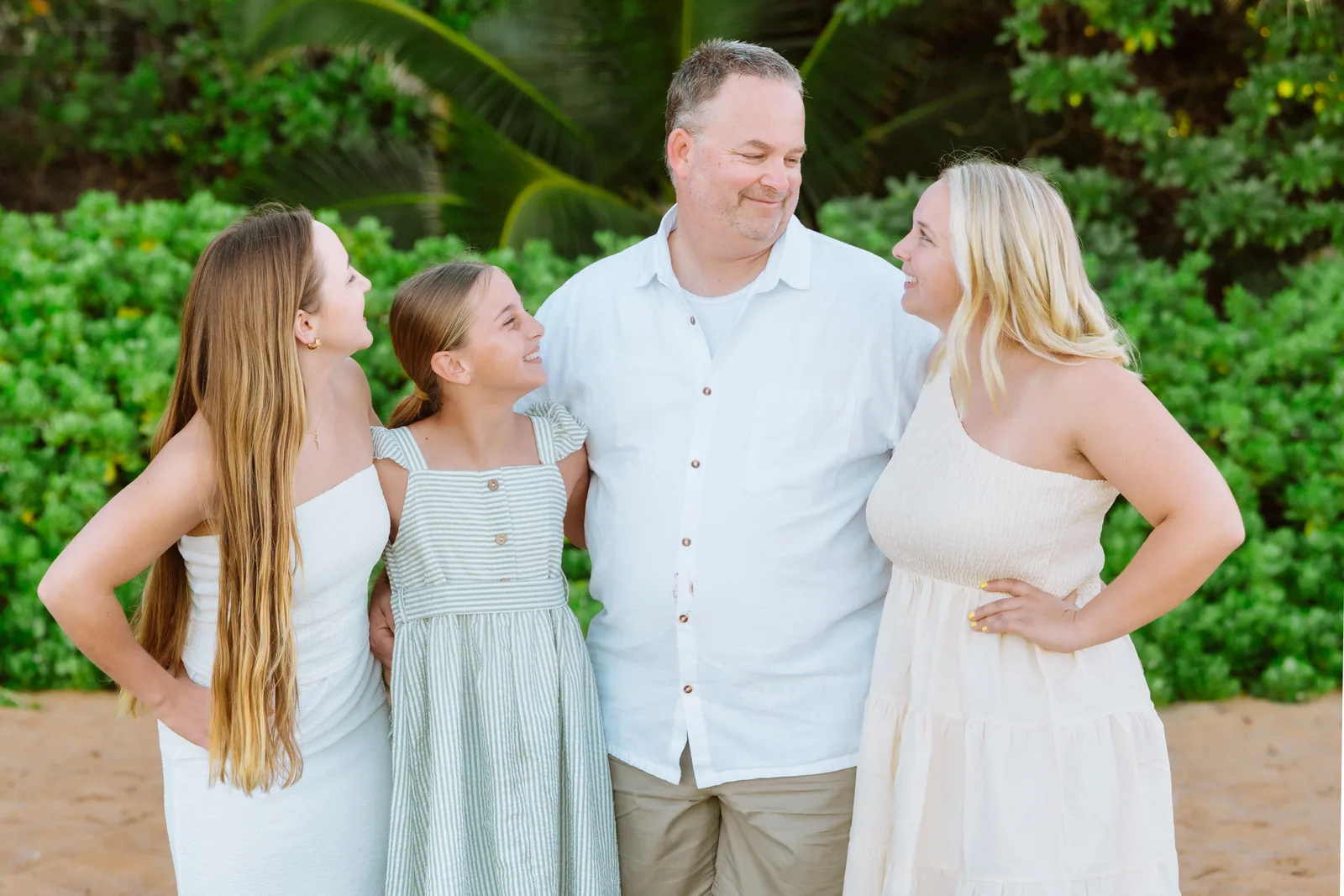 Parents and their daughters photographed in front of dense green foliage