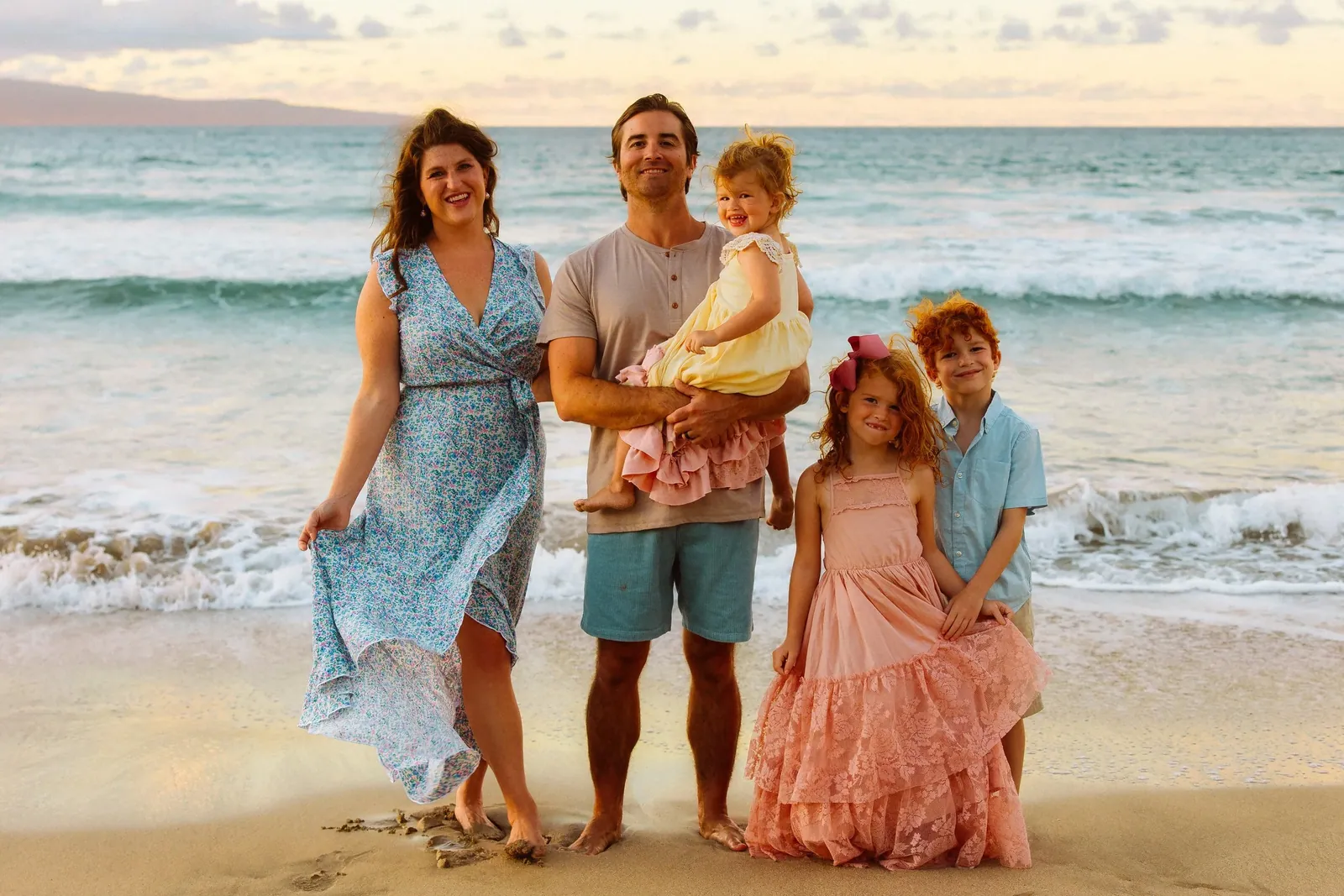 Parents and young children standing together at the water's edge on Maui
