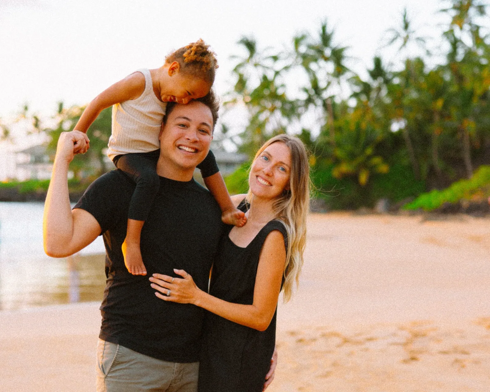 Parents holding their toddler between them on a Maui beach