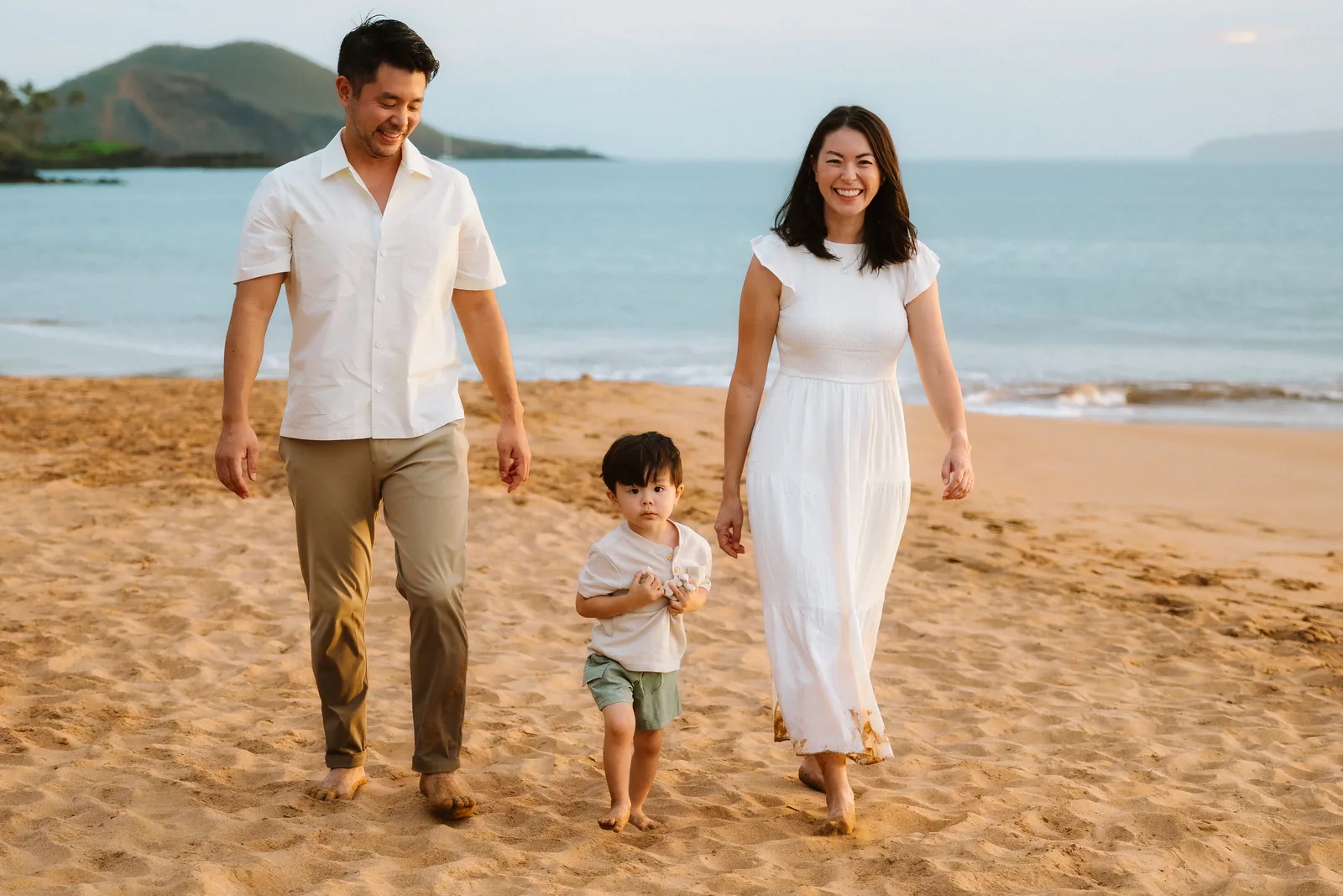 Parents walking the beach with their toddler between them