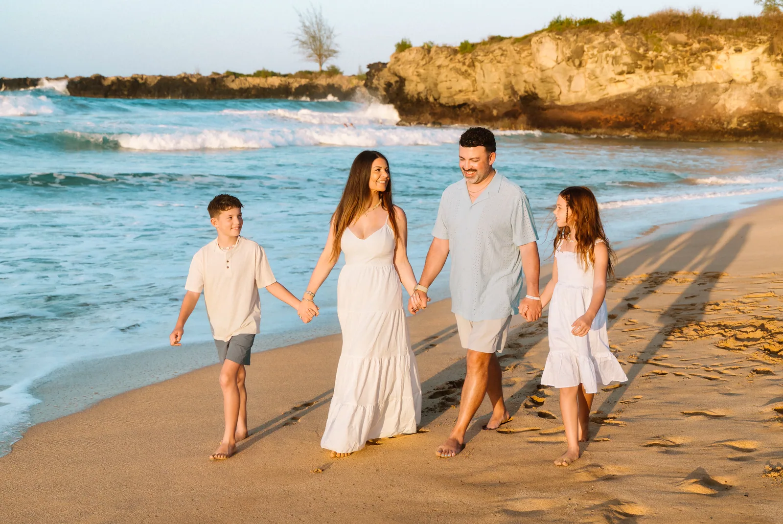 A family of four walking the shoreline hand in hand