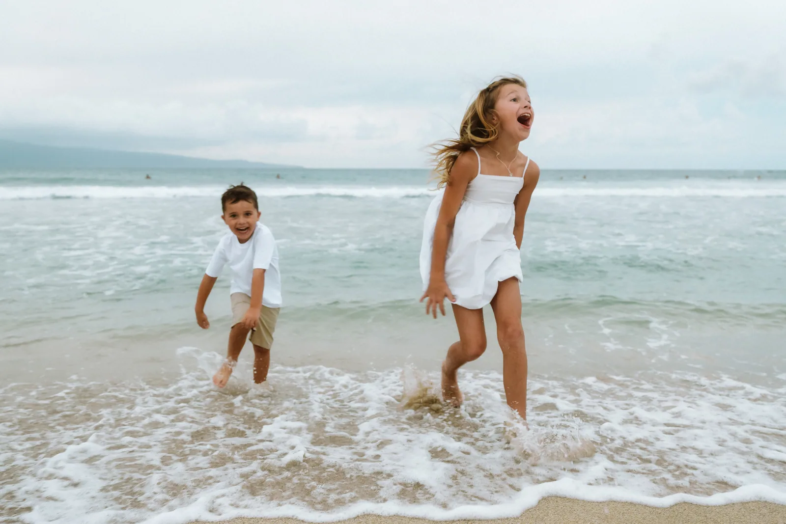 A brother and sister splashing through the shorebreak