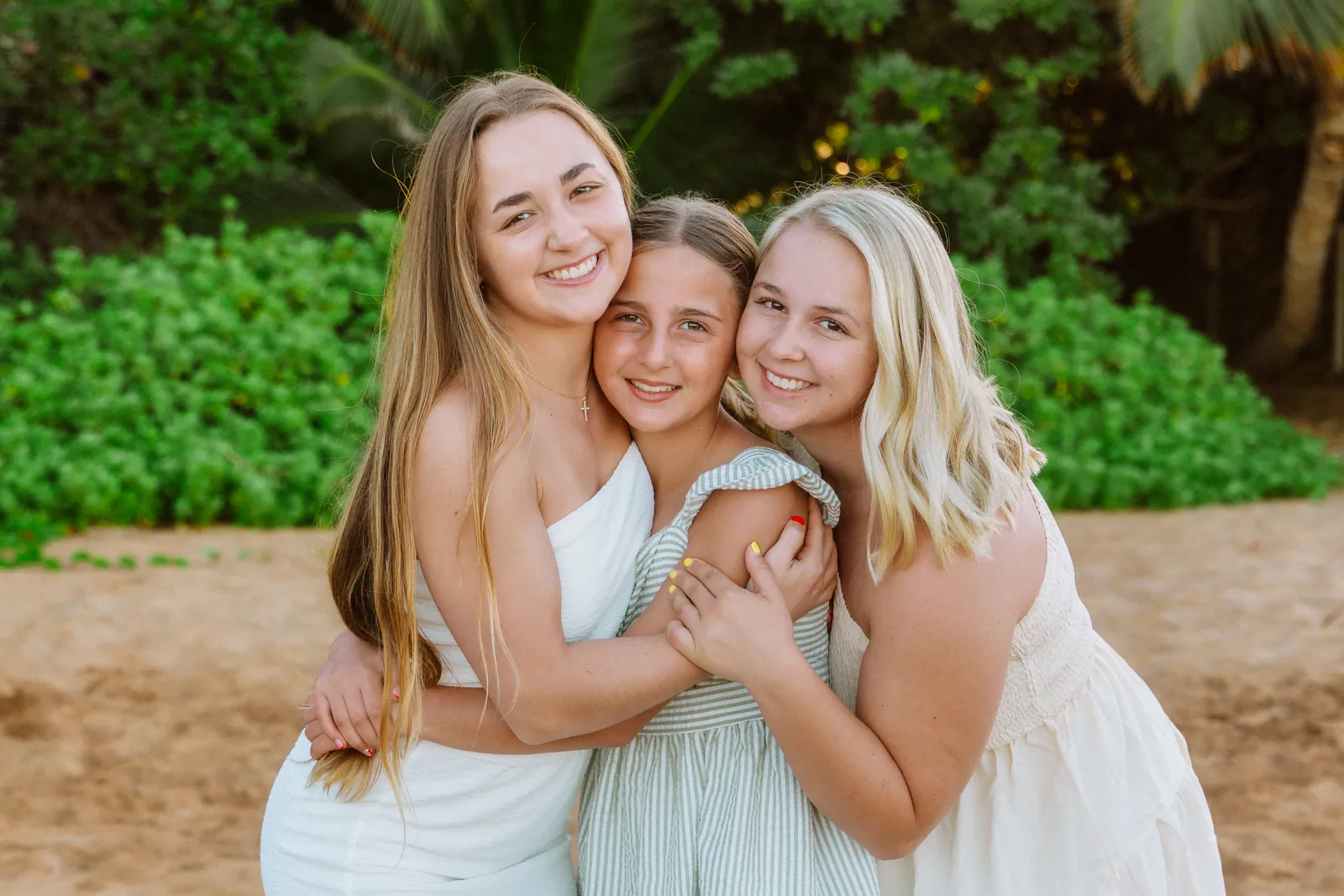 Three sisters photographed together against a wall of green