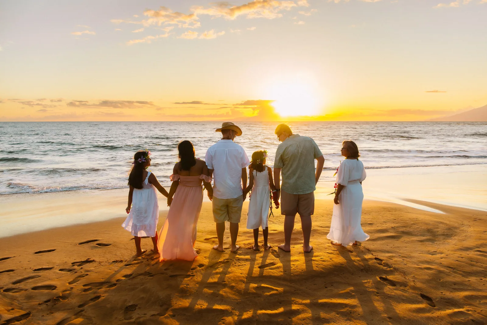 A family walking hand in hand into a full sunset, in silhouette