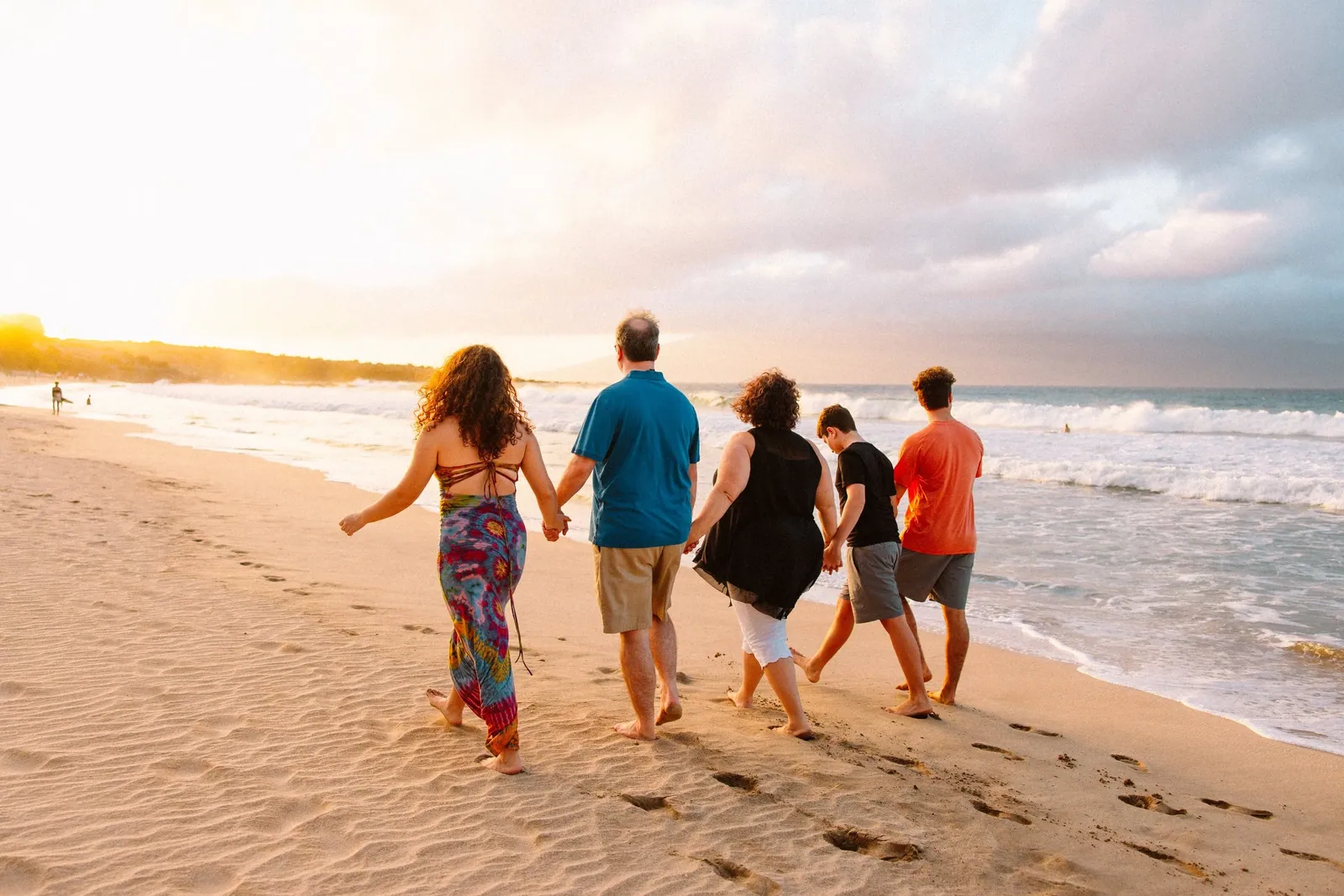 Family with teenagers standing barefoot on the sand at a Maui beach