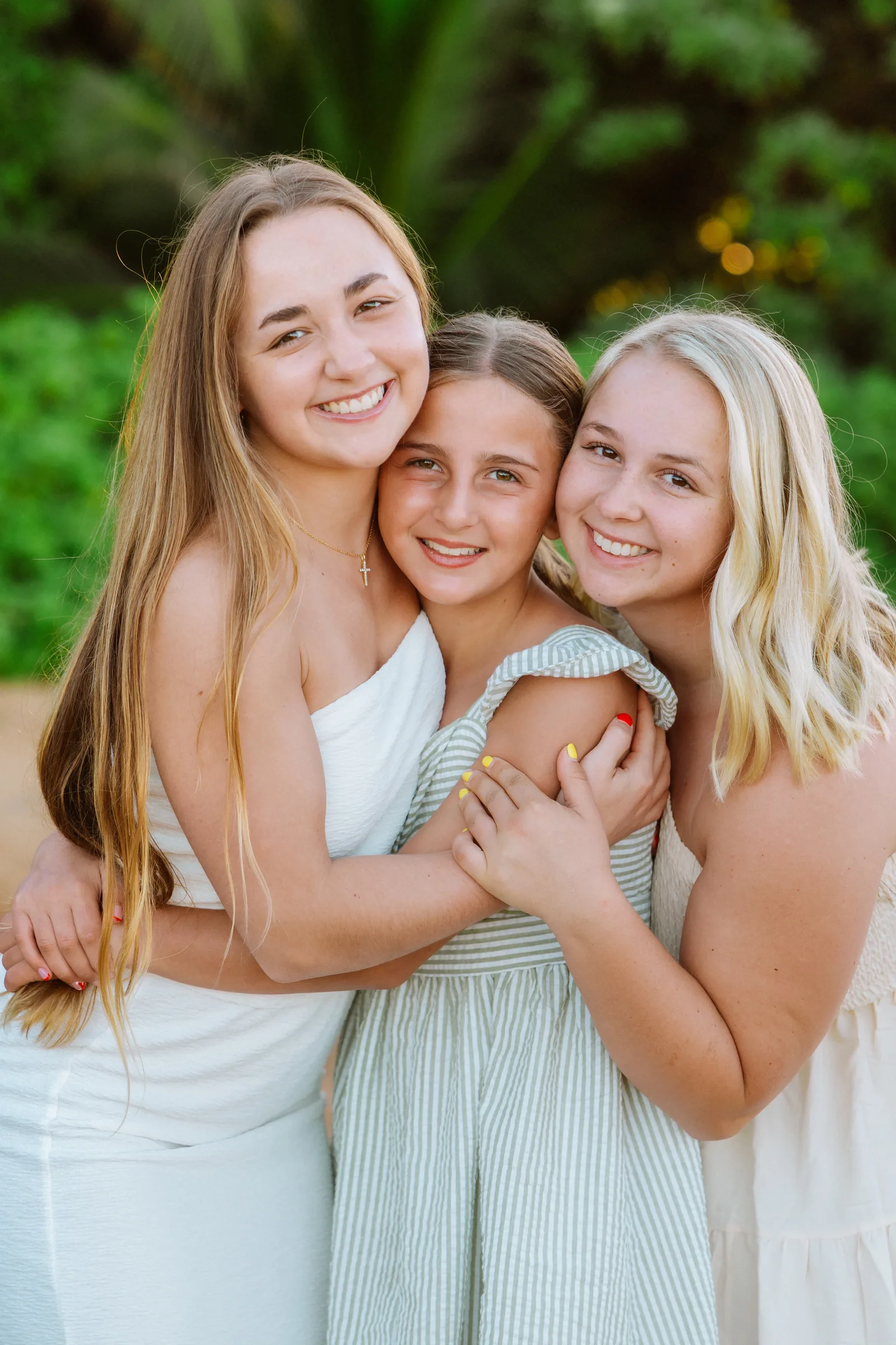 Three sisters holding onto each other, laughing, in a close portrait