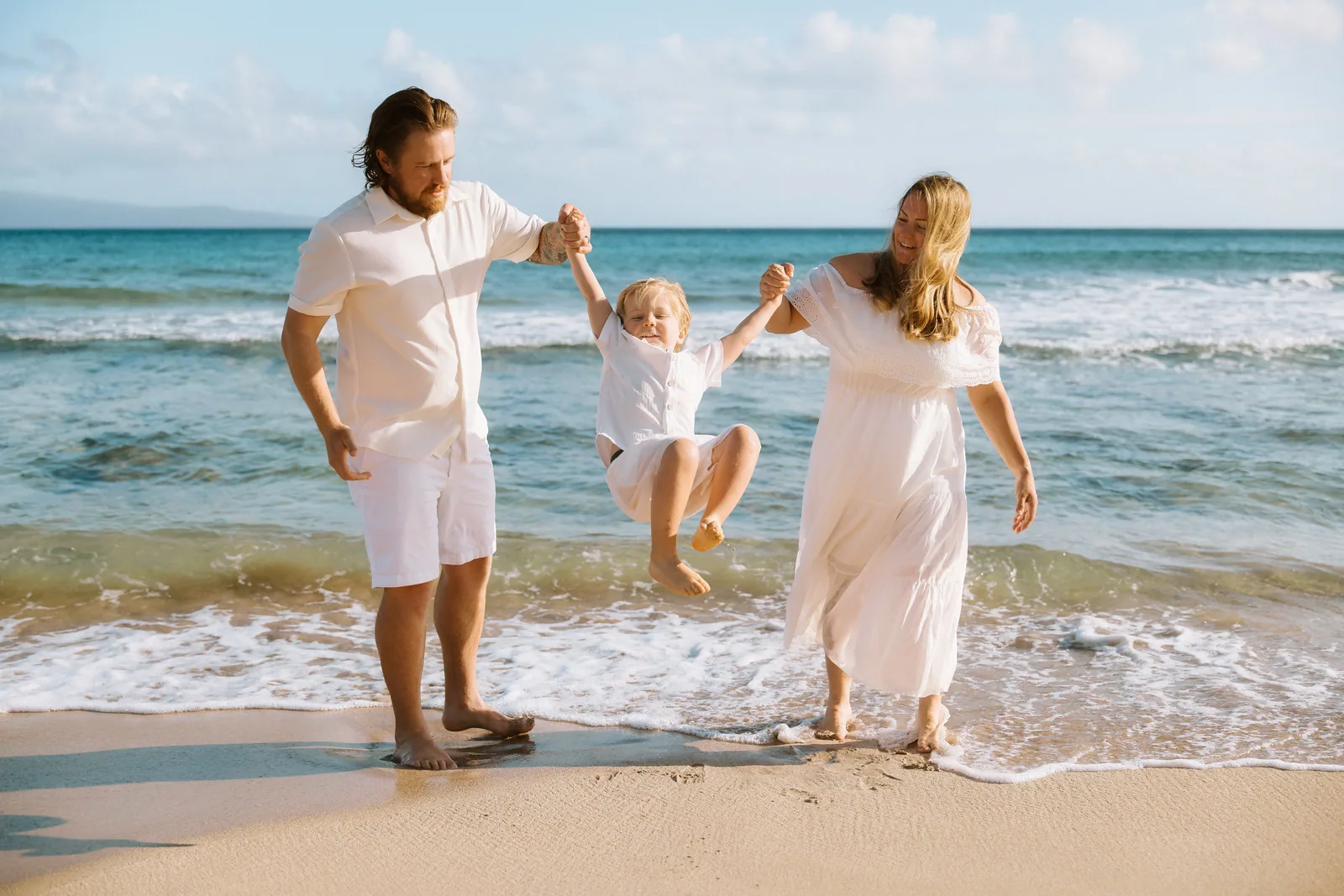 Parents swinging their toddler between them at the water's edge
