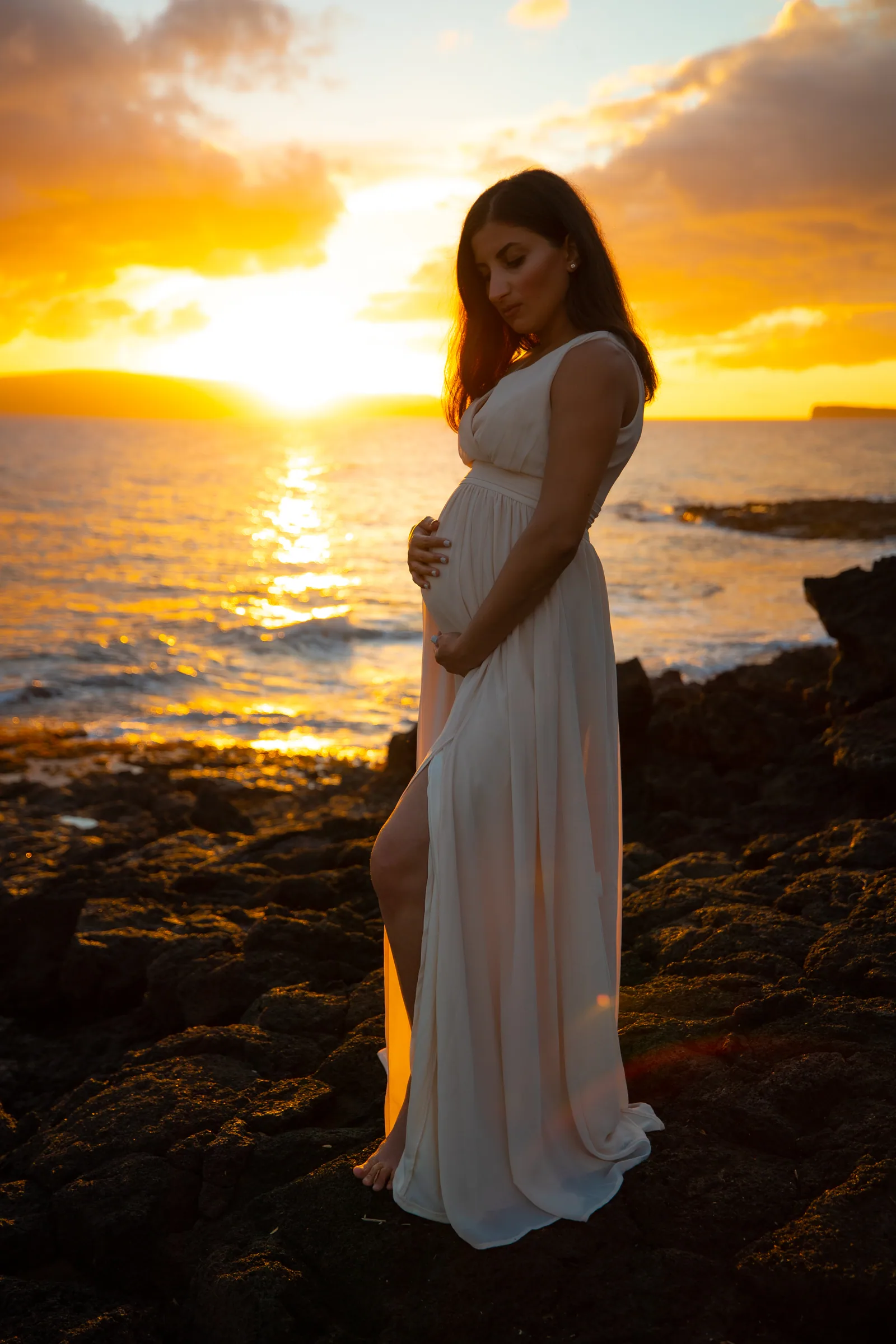 An expectant mother silhouetted against a full sunset