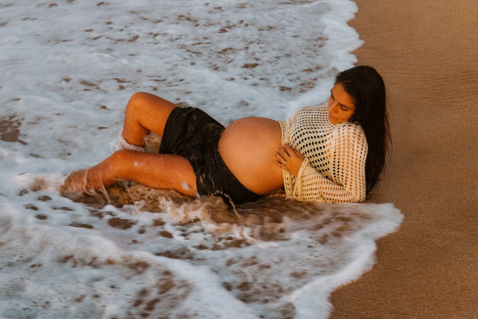 An expectant mother lying in the shallow wash at the waterline