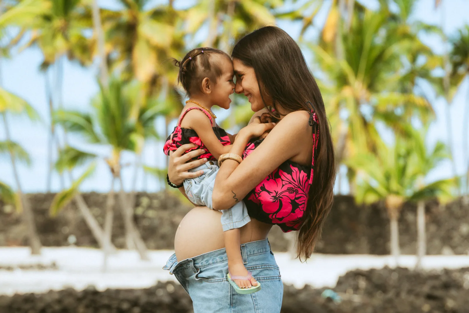 An expectant mother holding her older child, foreheads together