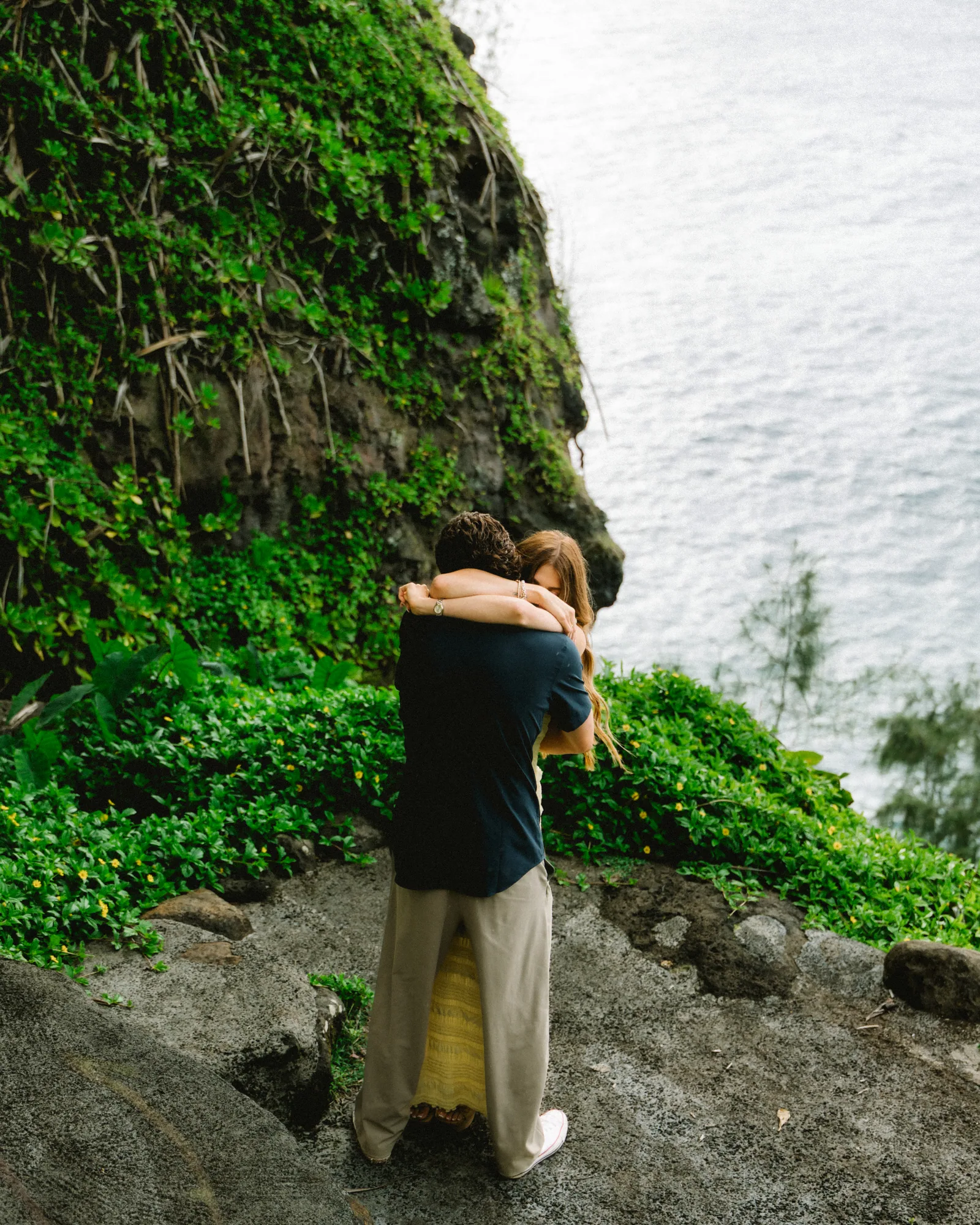 A couple embracing on a cliff edge immediately after the proposal