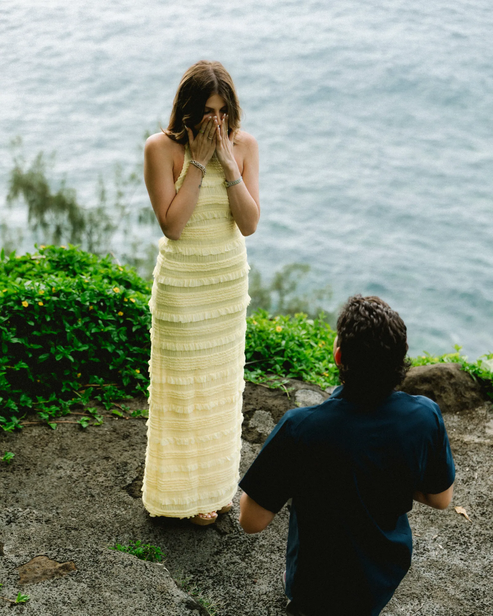 The moment after the question: hands to her face, him still on one knee