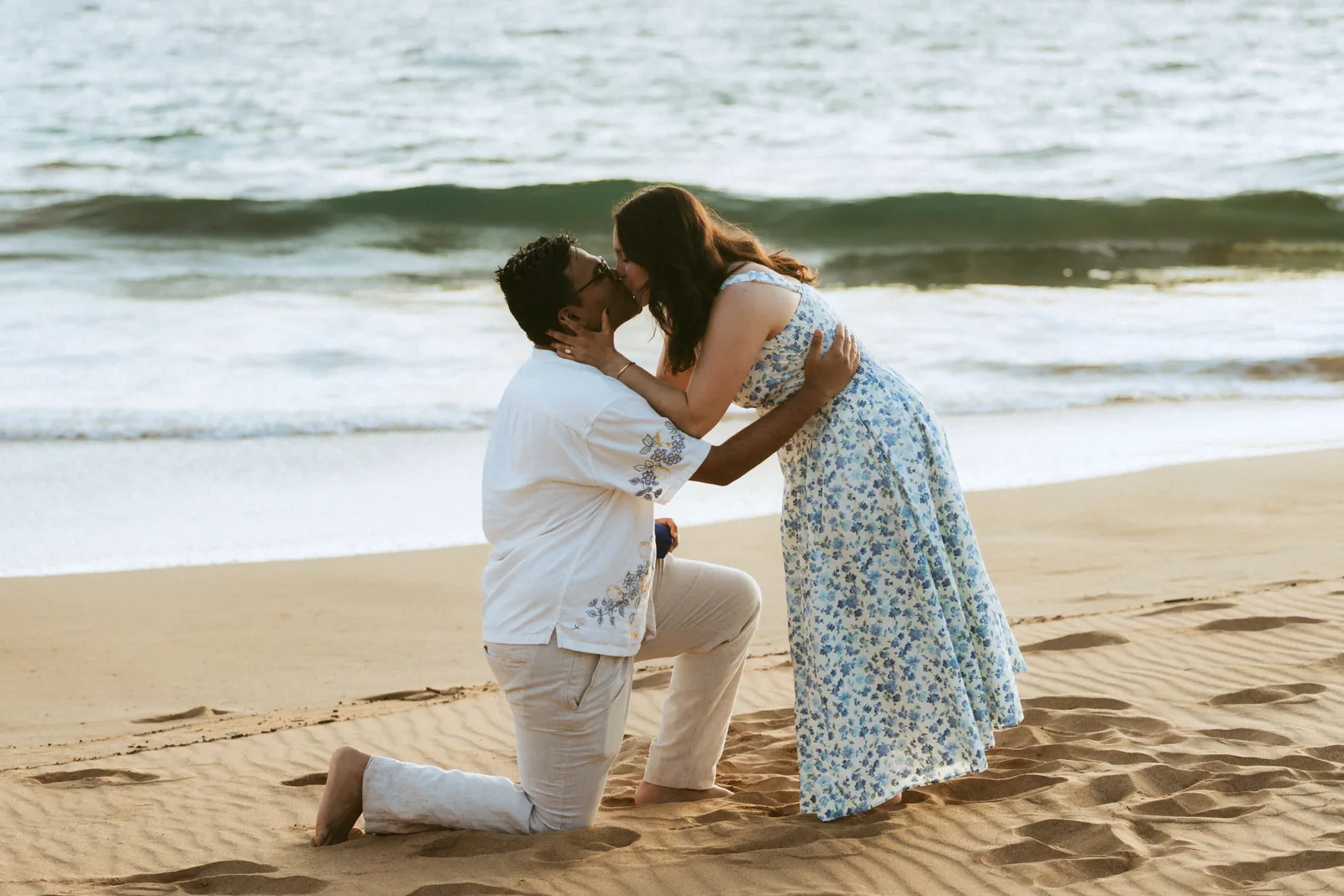 A proposal in the shorebreak, him on one knee in the wet sand