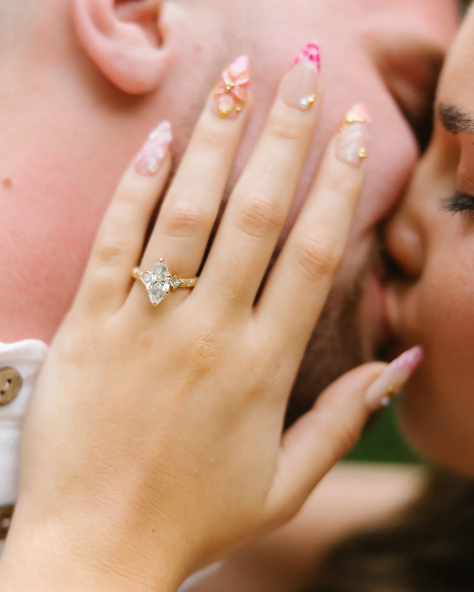 Her ring hand against his face as they kiss