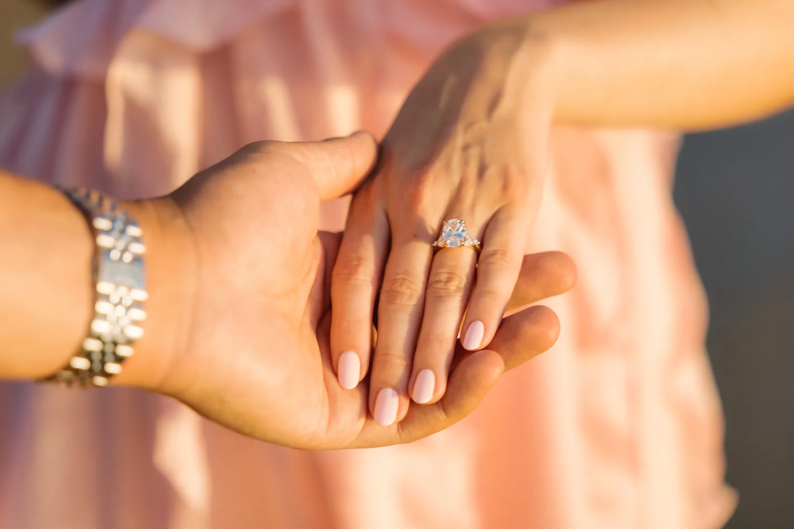 Her hand resting on his, the new ring catching soft light