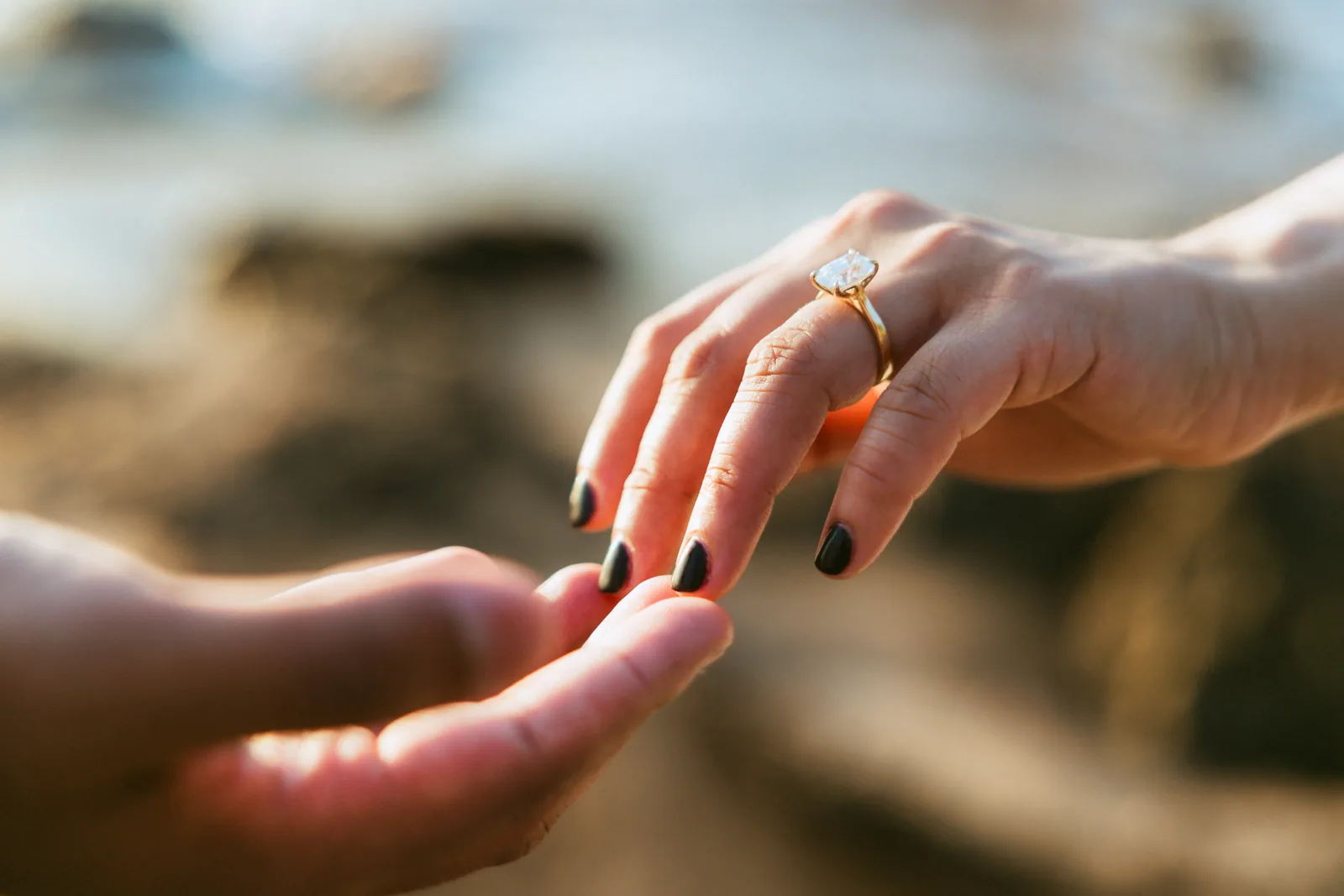 Her hand held out with the ring on it, the beach soft behind