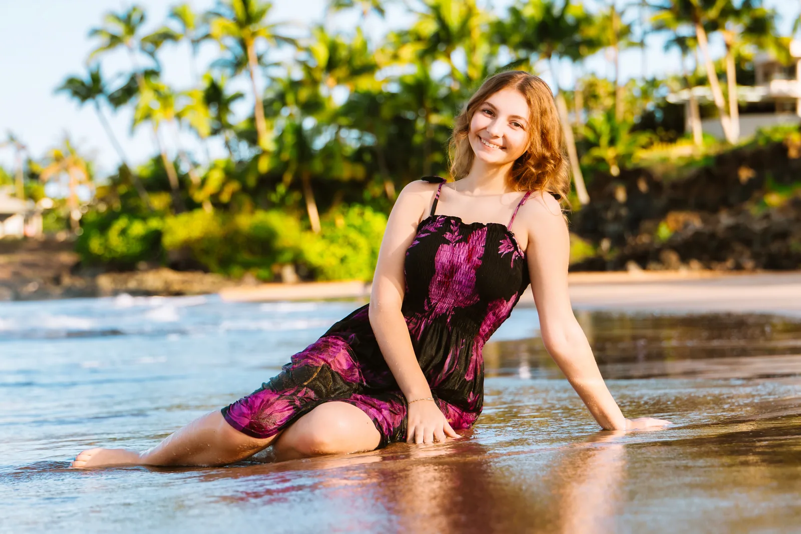 A senior portrait seated at the waterline in a floral dress