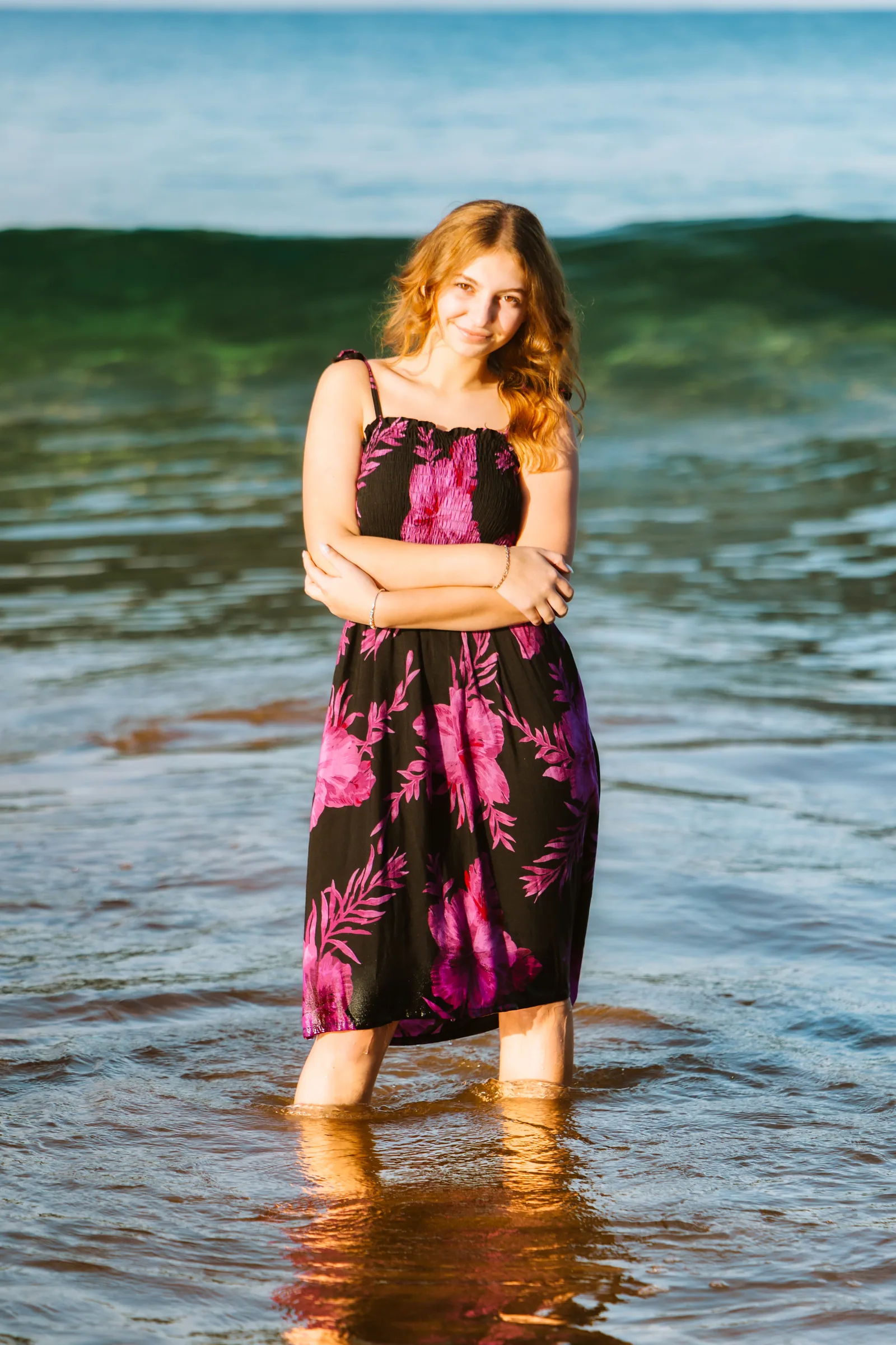 A senior portrait standing in the shallows in a floral dress