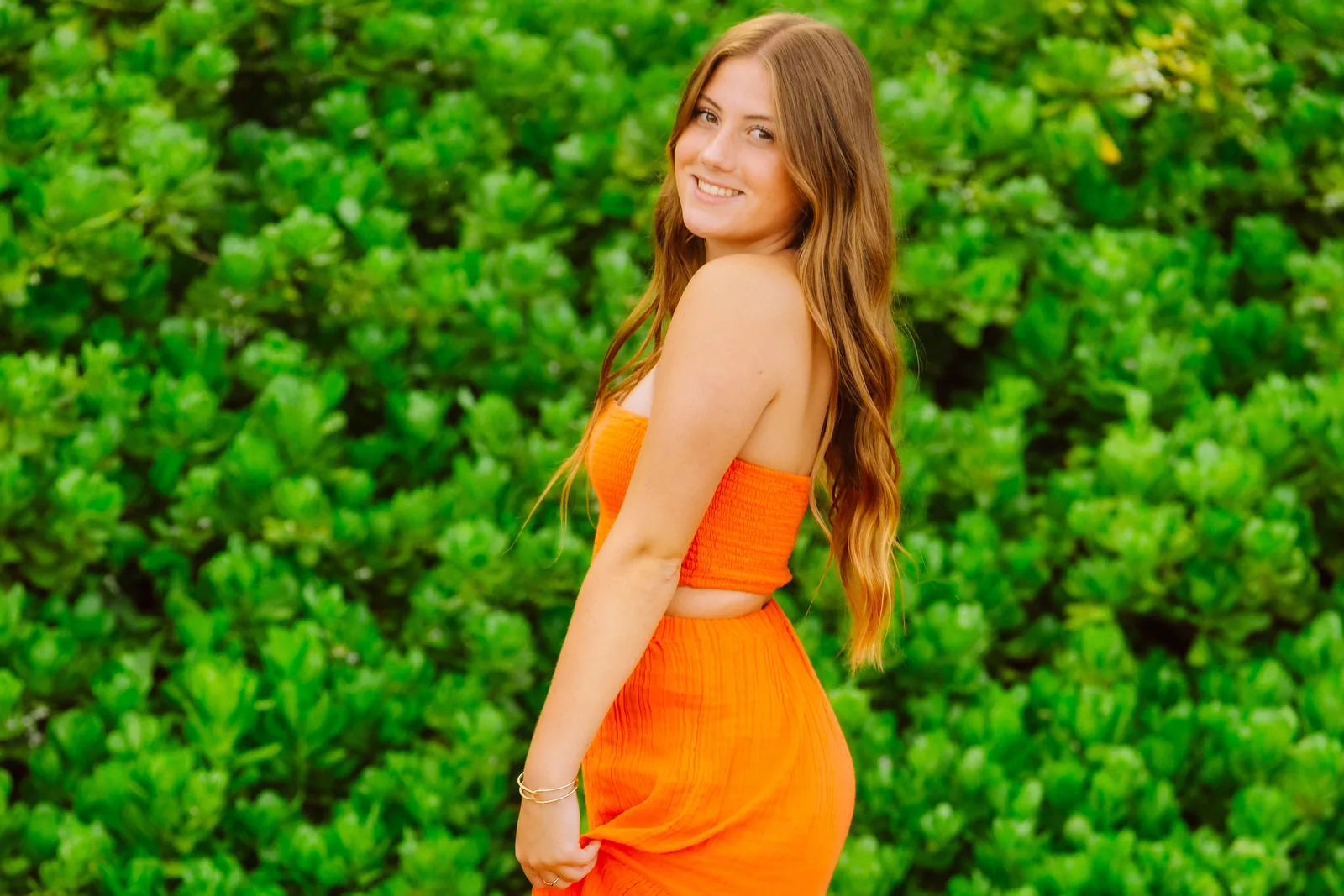 A senior portrait against a bank of bright green coastal growth