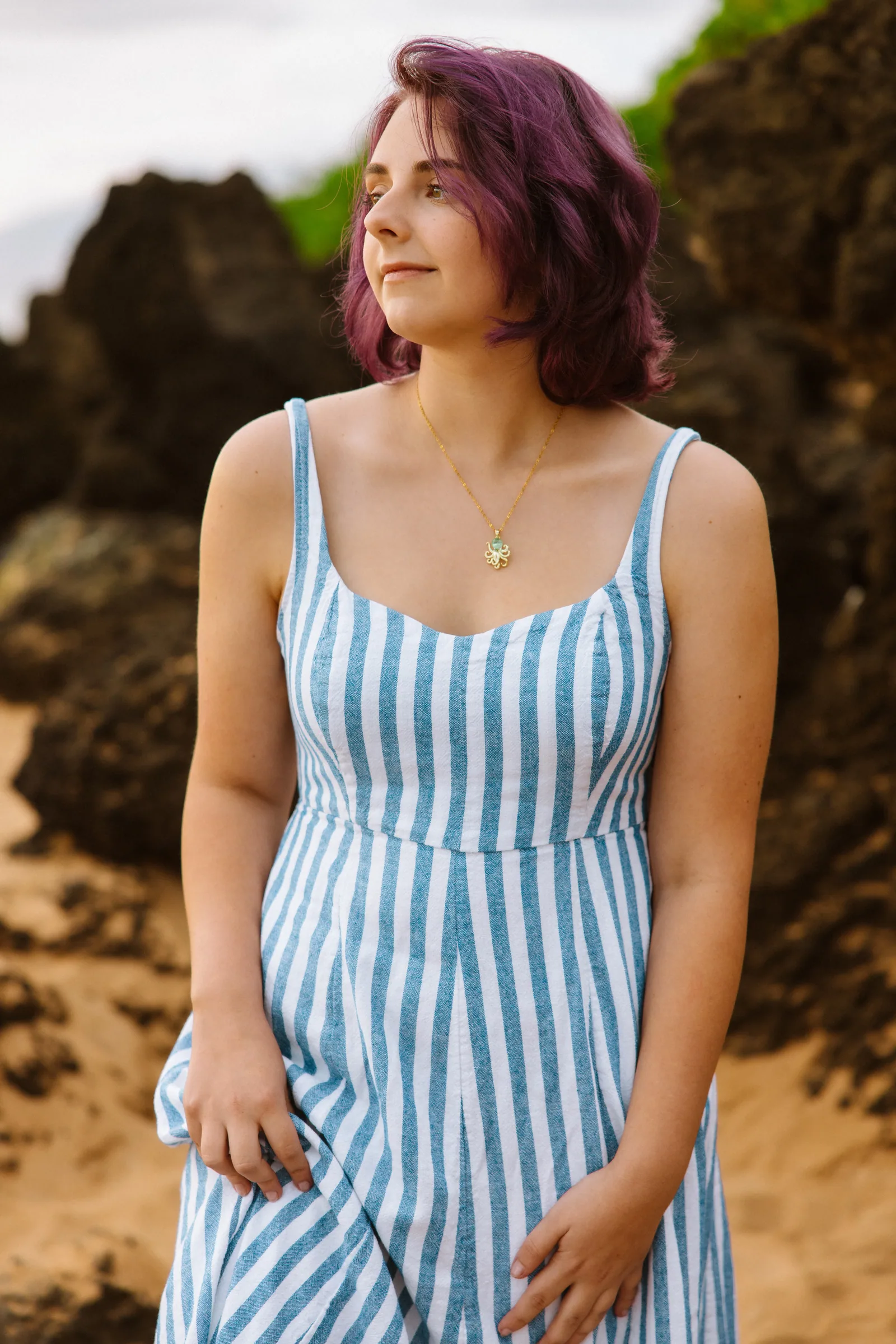 A senior portrait beside lava rock in a striped dress