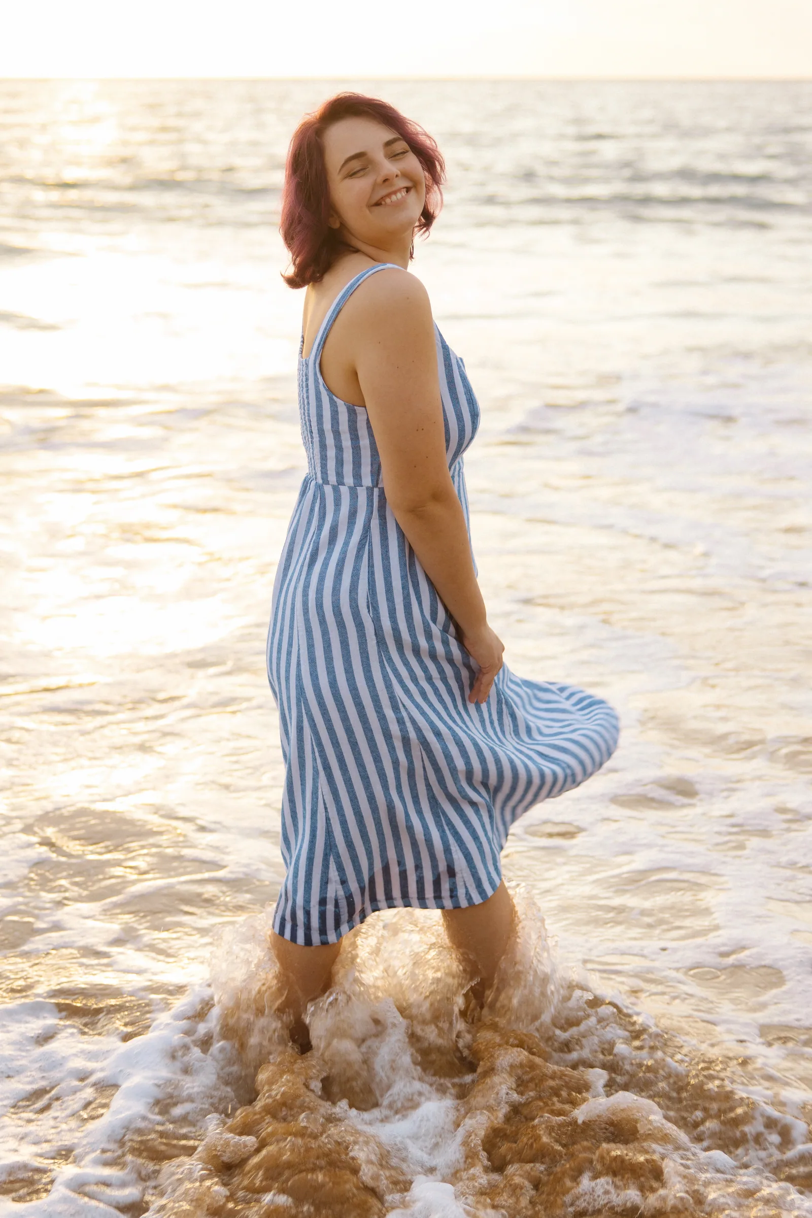 A senior portrait standing in the shallows, dress lifting in the wind