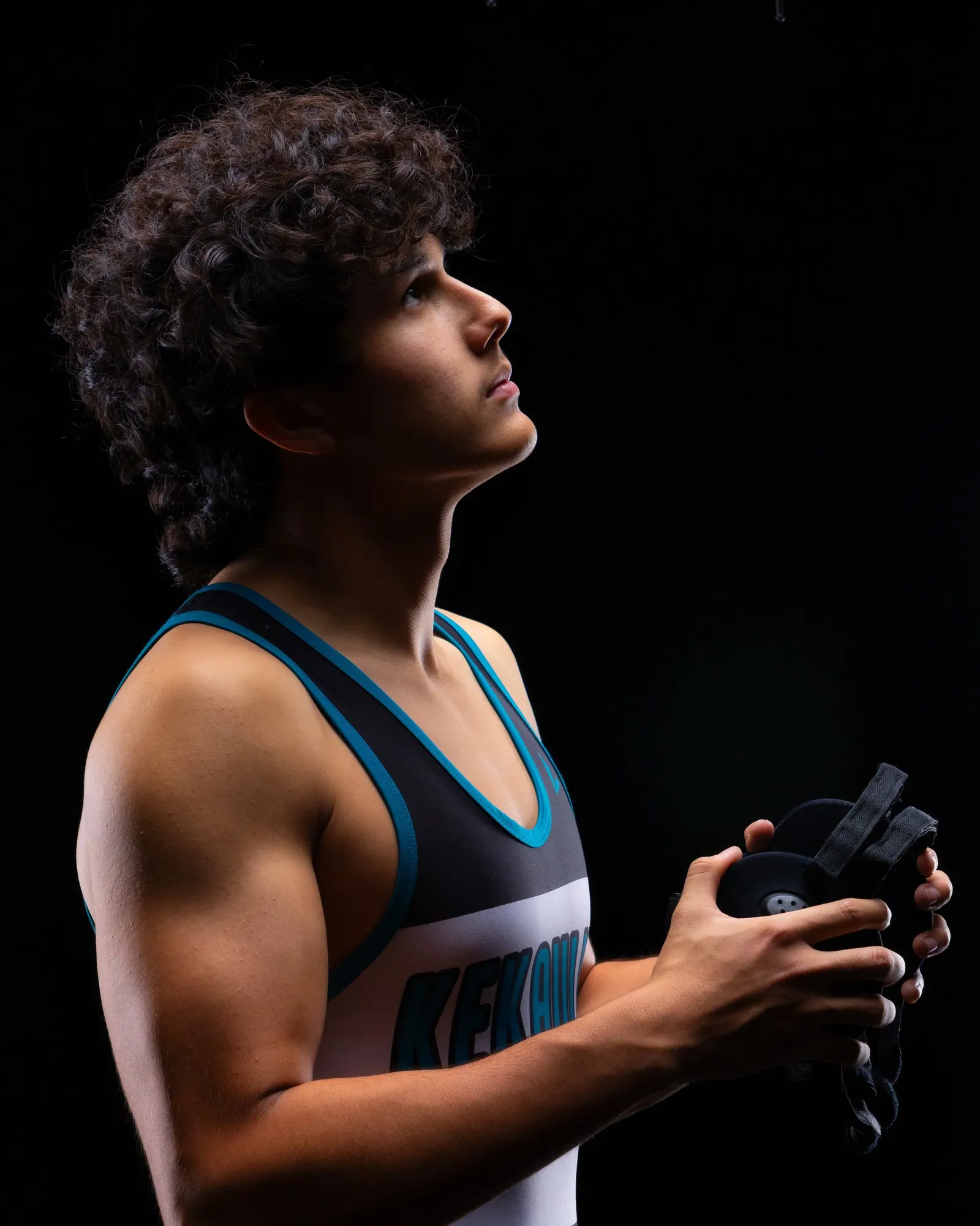 Wrestler in his singlet holding his headgear, studio portrait against black